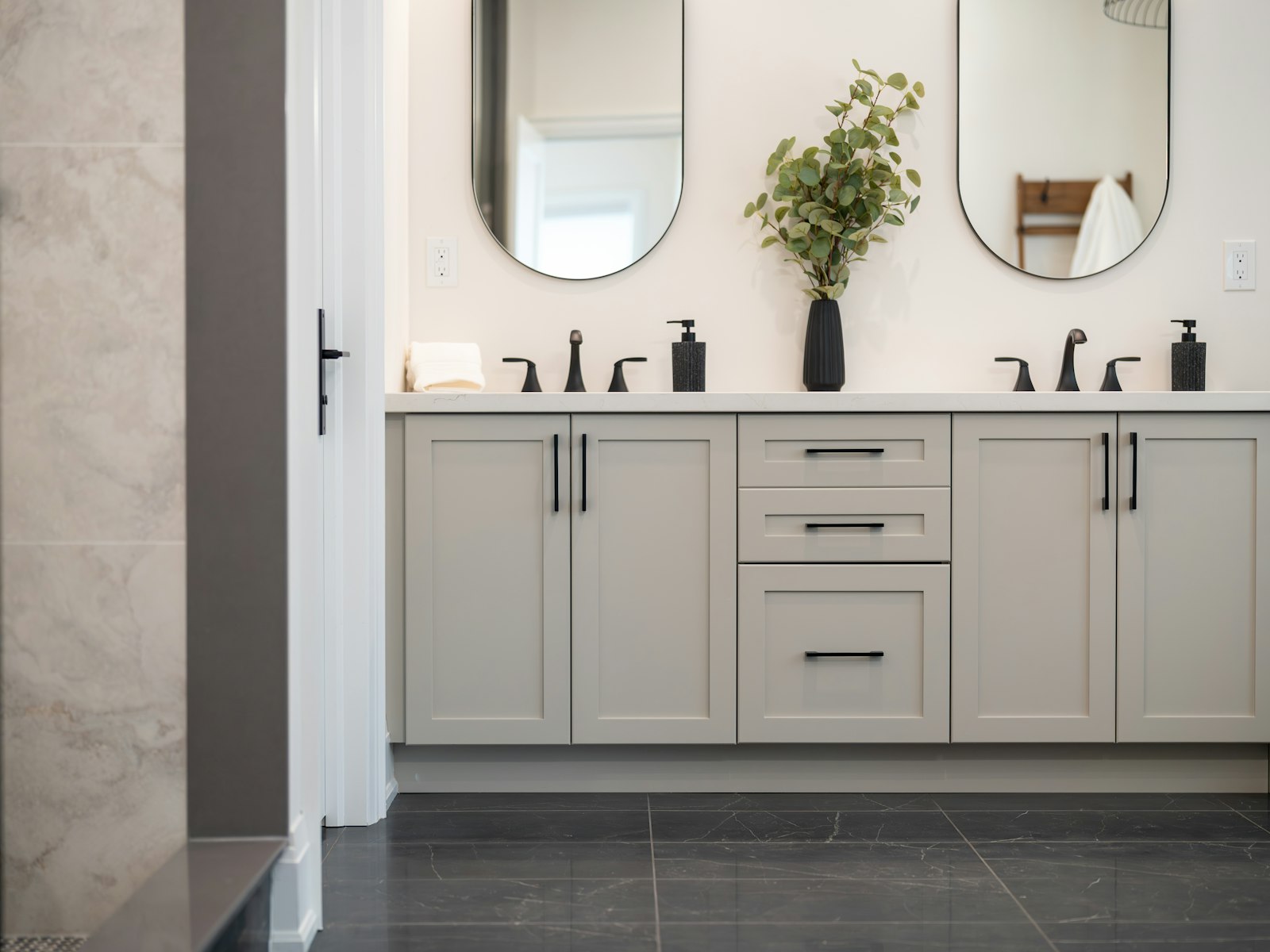 Renovated bathroom with a double vanity, oval mirrors and tile flooring