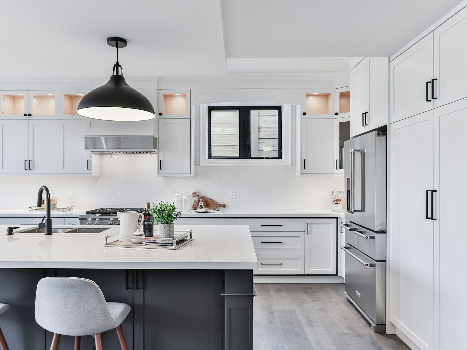 Refreshed white kitchen with a grey island, pendant lights and stainless appliances