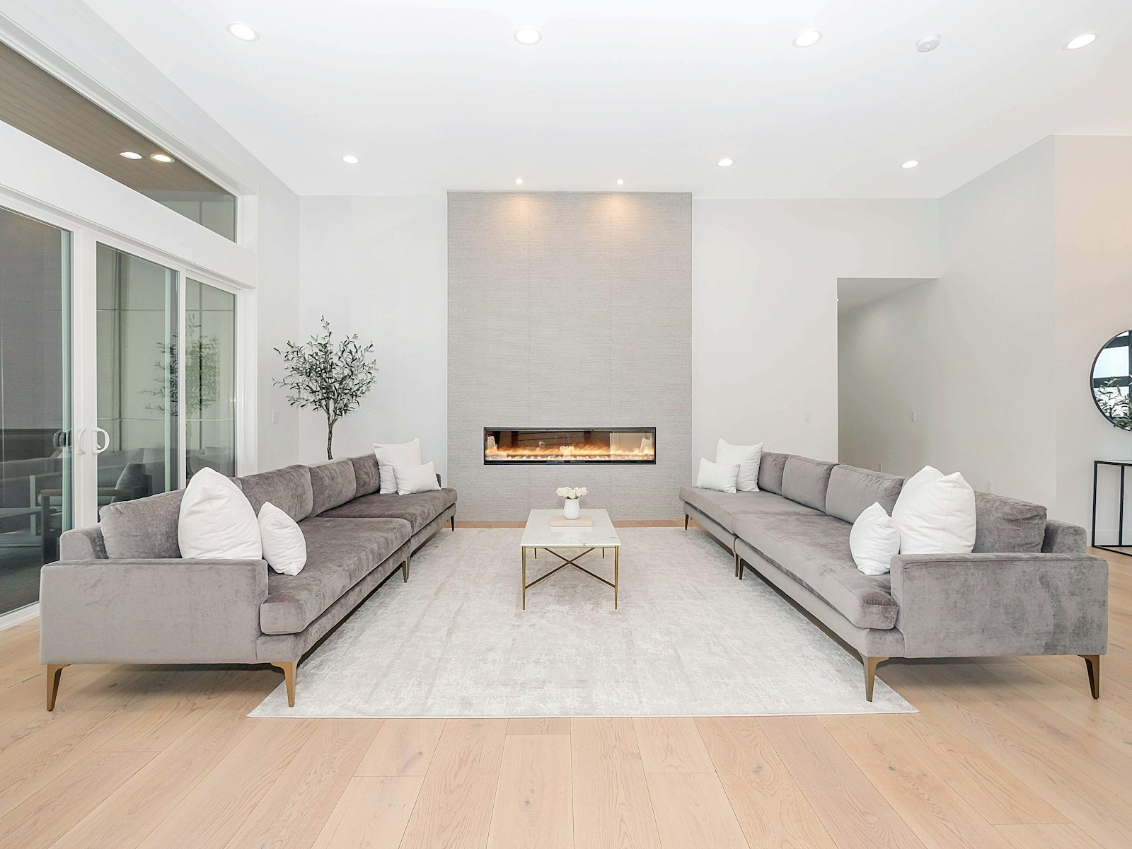 Bright living room with light wood-look flooring, two grey sofas and a modern built-in fireplace